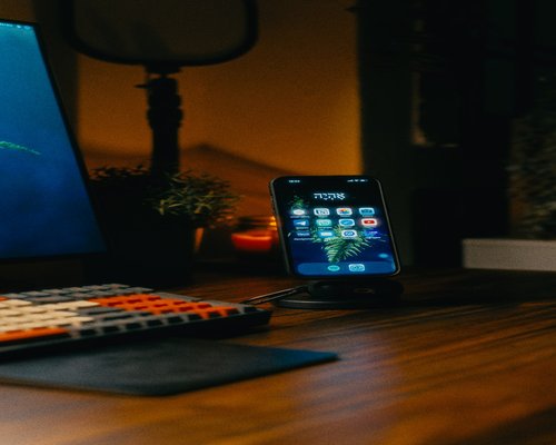 Smartphone resting on a wooden desk with a soft ambient lamp in the background